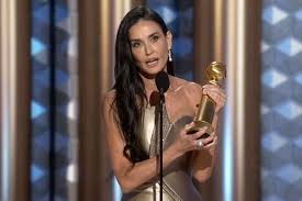 Demi Moore holding a Golden Globe for Best Actress award while giving an acceptance speech.