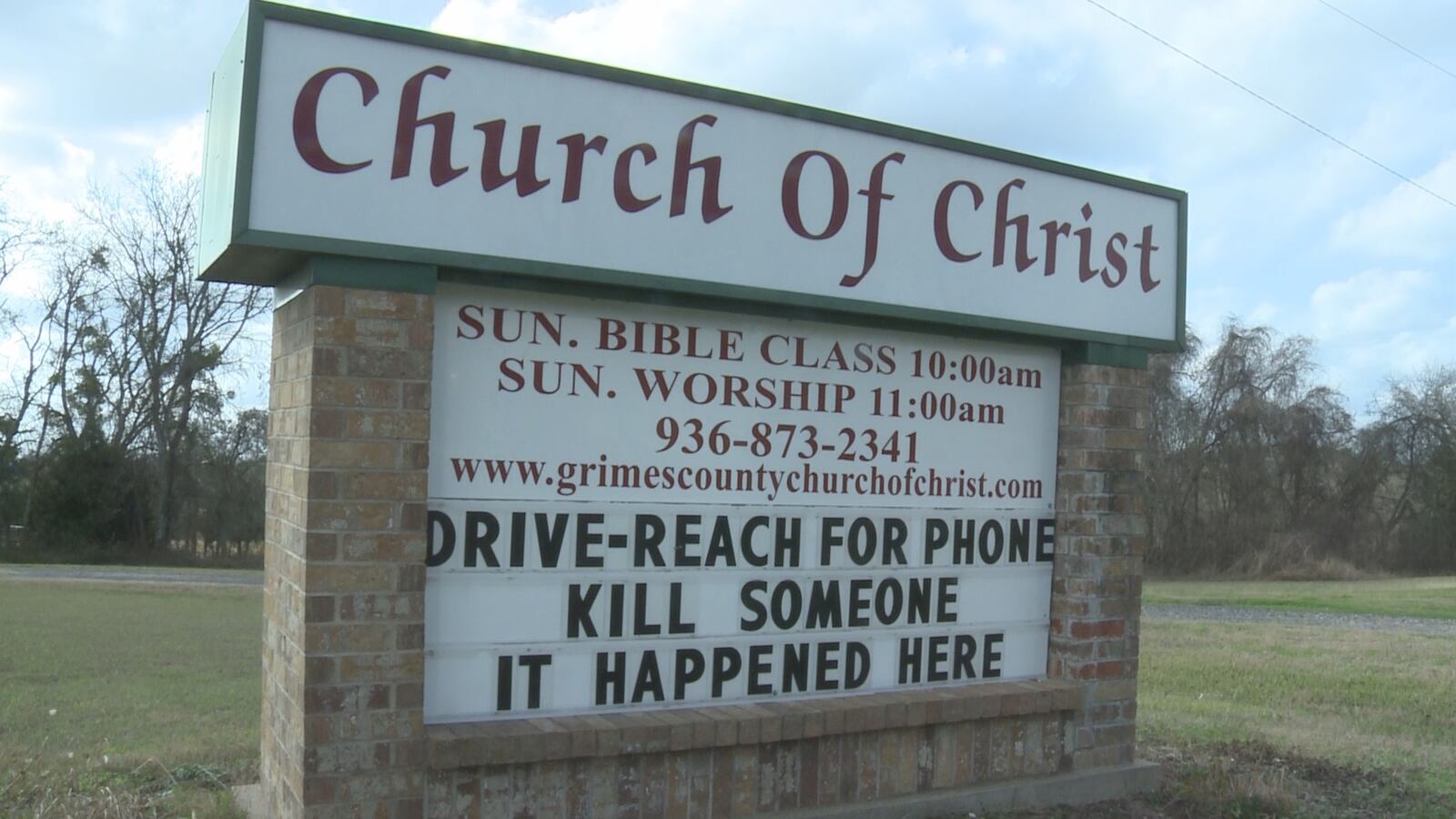 Sign outside the Grimes County Church of Christ displaying service times and contact number, with text urging drivers to not use phones, mentioning a past incident.