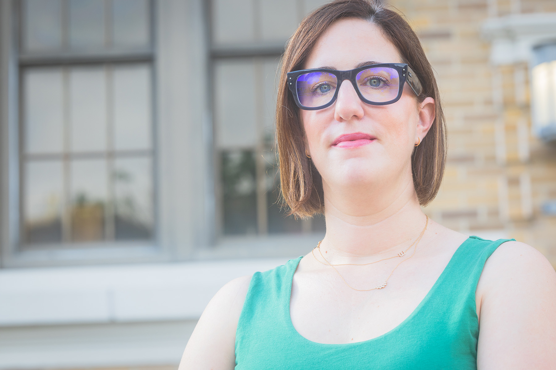 Jessica Bernard, wearing a blue tank top, stands in front of the psychology building.