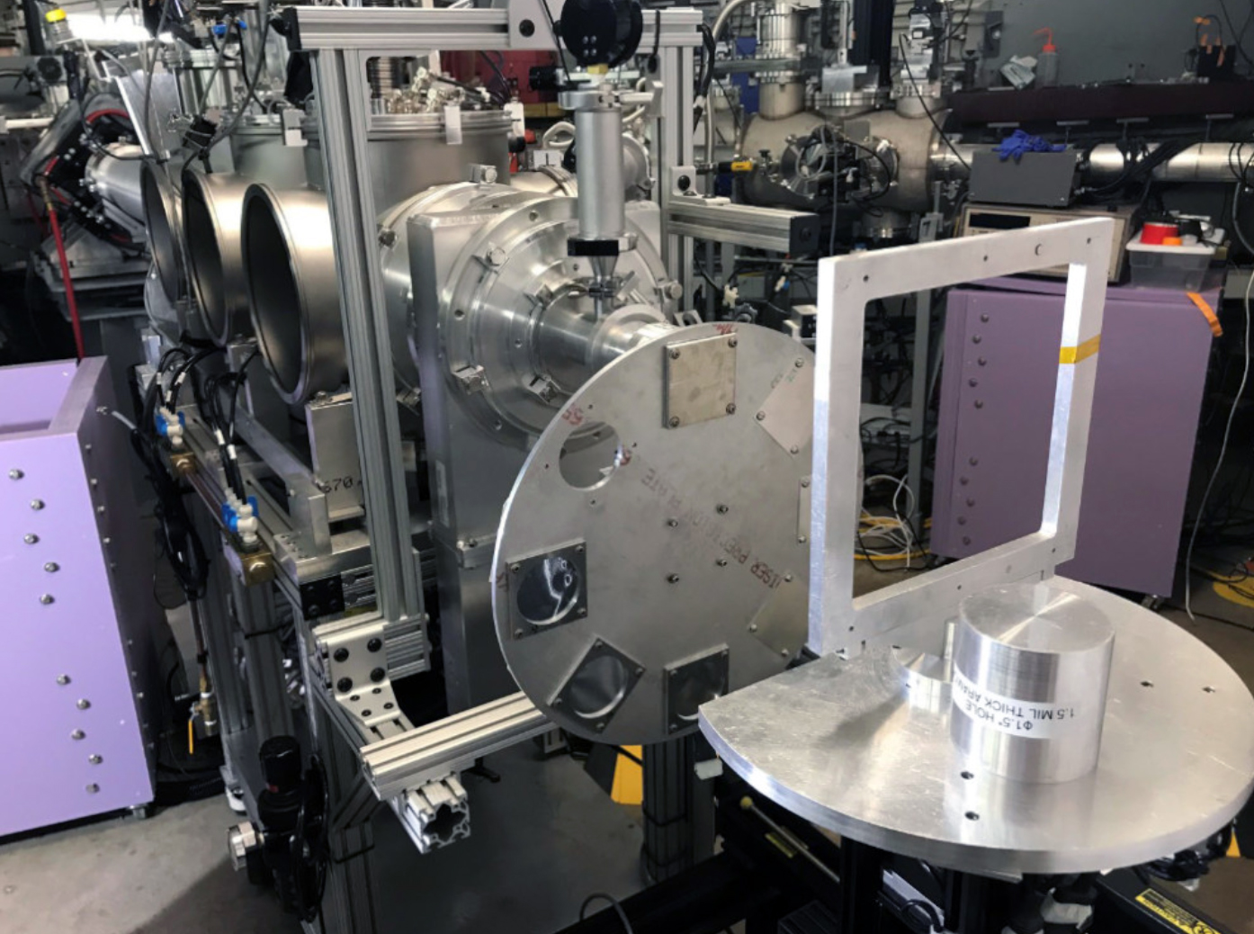 The K150 cyclotron beam line — characterized by complex scientific apparatus, metal cylinders, a square frame and various cables — within the Cyclotron Institute at Texas A&amp;M University.