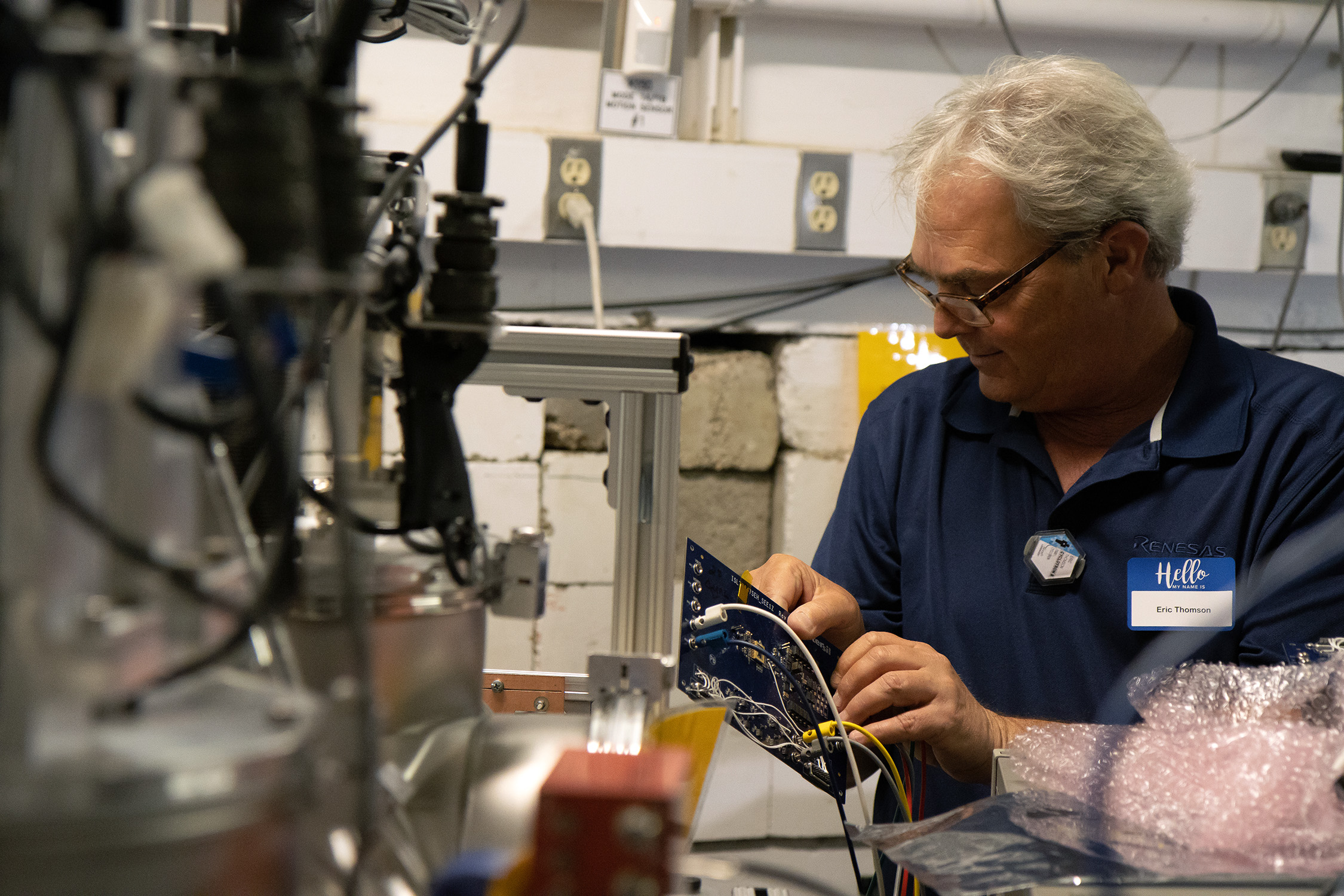 Renesas Electronics’ Eric Thomson carefully works on a circuit board, surrounded by wires and machinery, within the Cyclotron Institute at Texas A&amp;M University.
