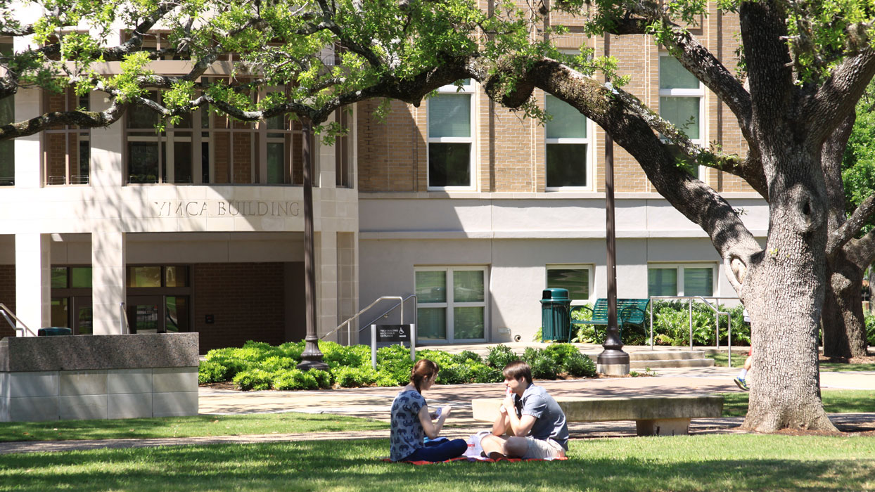 Students sitting in the grass outside the YMCA building