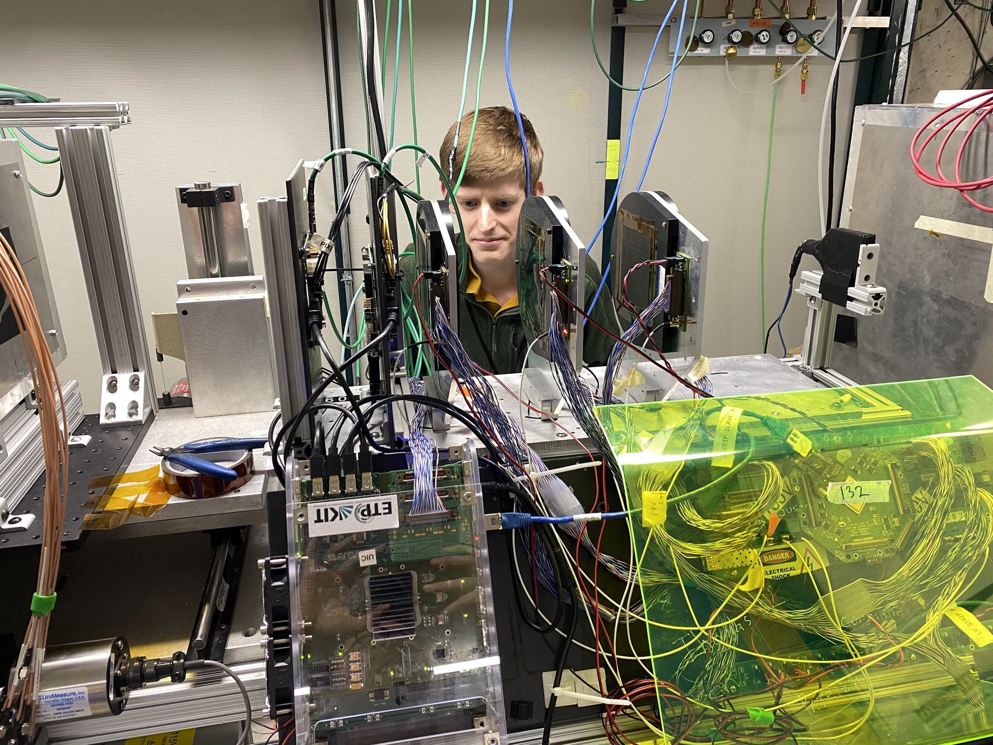 Austin Baty working in a physics lab with several computer chips and wires around him.