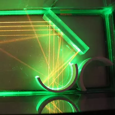 Multiple laser beams reflected off of an angled glass plate and a cylinder cut in half