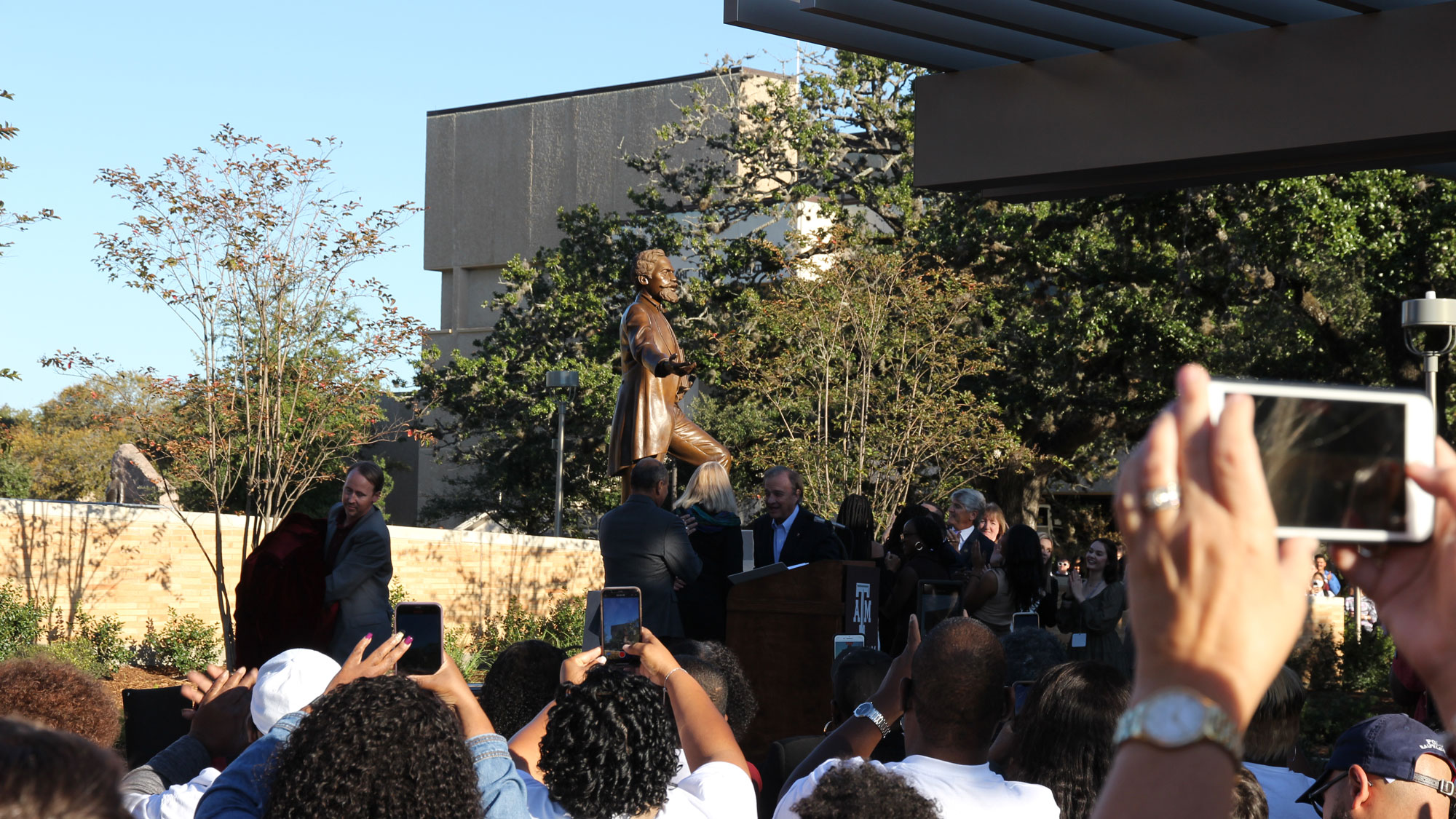 A crowd gathers around the unveiling of the new statue of Sen. Matthew Gaines, located near the Memorial Student Center and Student Services Building in the middle of Texas A&amp;M's campus.