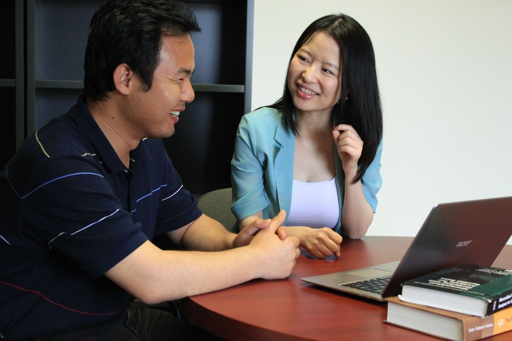 A man and woman smiling next to each other as they discuss statistics.