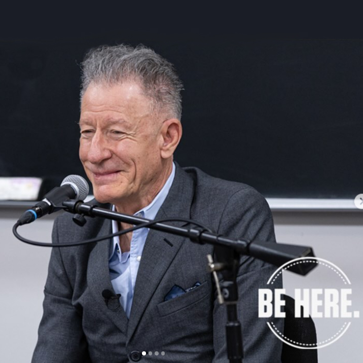 Lyle Lovett sits in front of a microphone on a boom in a classroom
