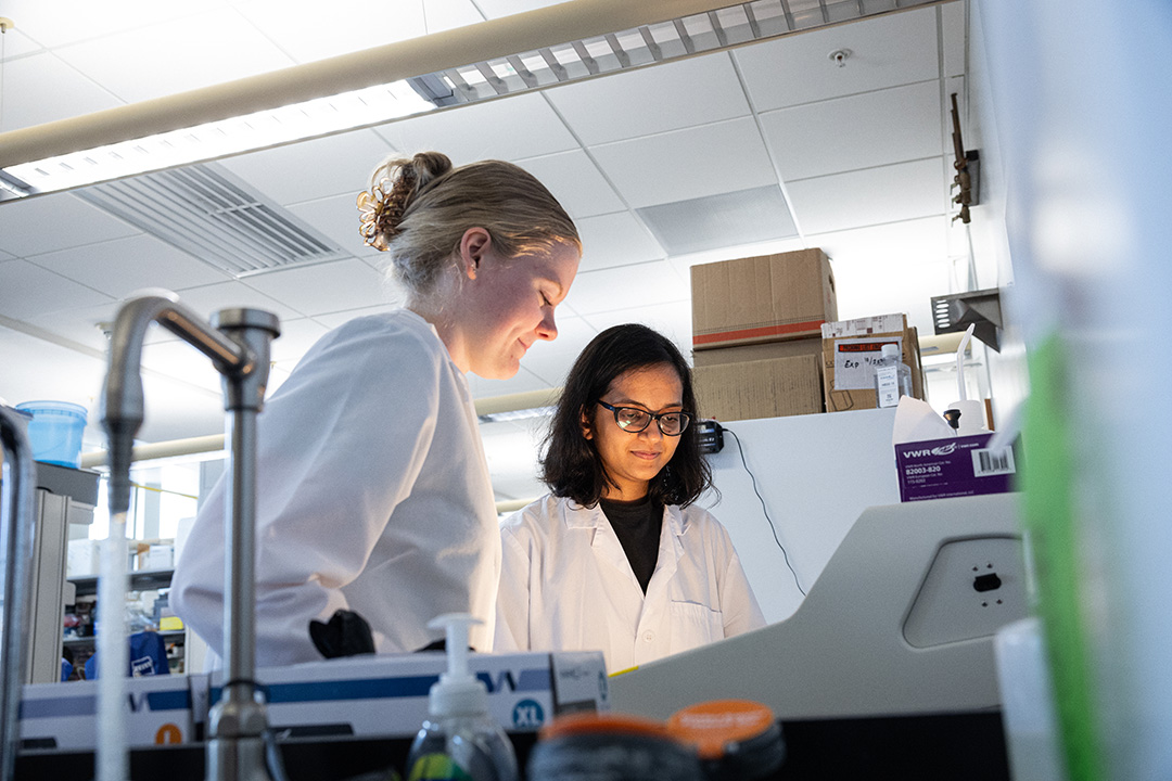 two female lab assistants looking into a glowing light